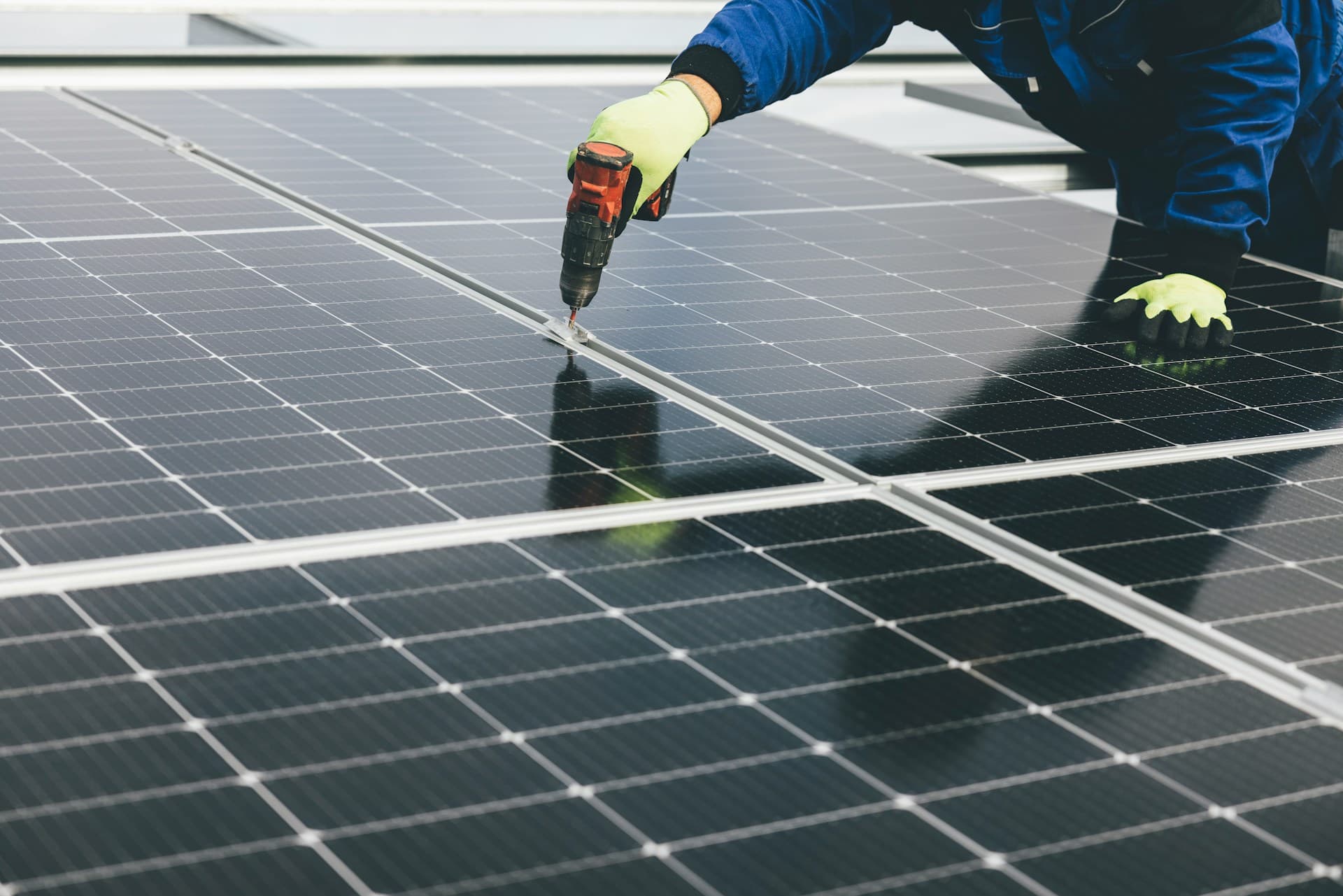 O braço de um homem usando uma parafusadeira elétrica para instalar uma placa solar.